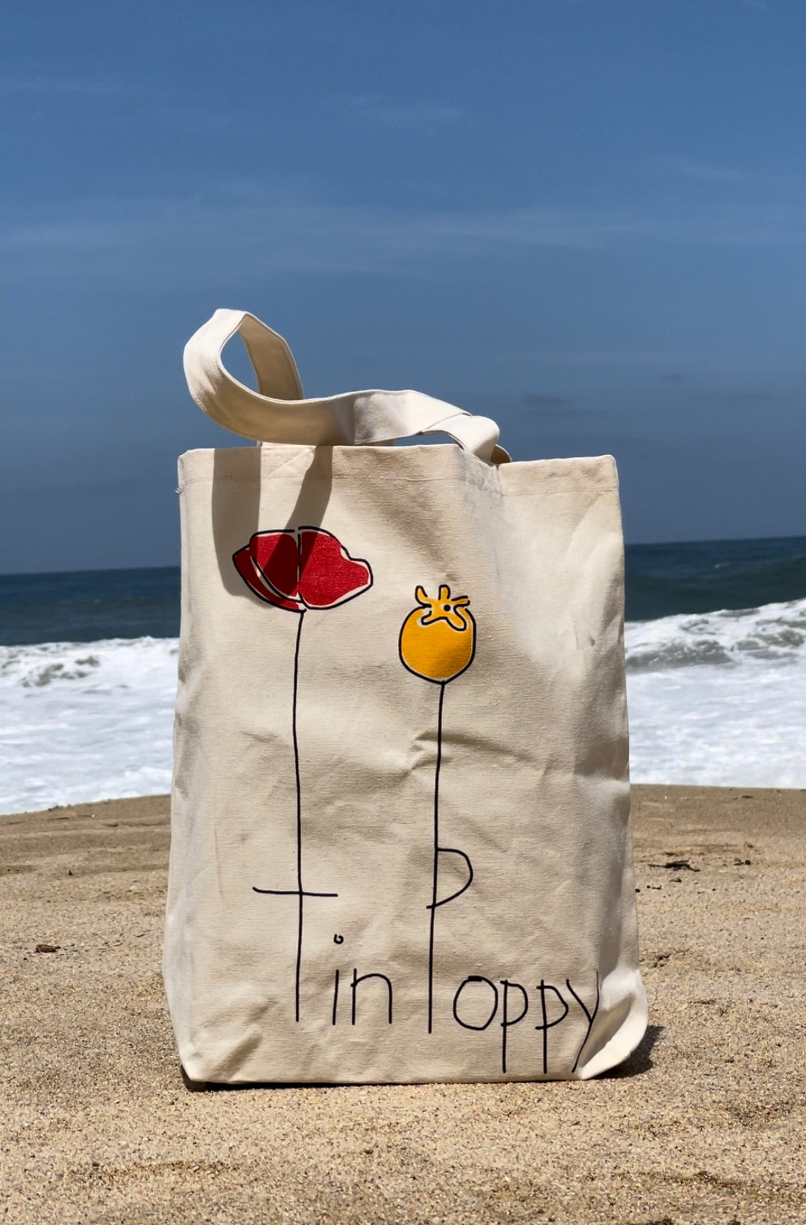 Tin Poppy tote bag on a beach